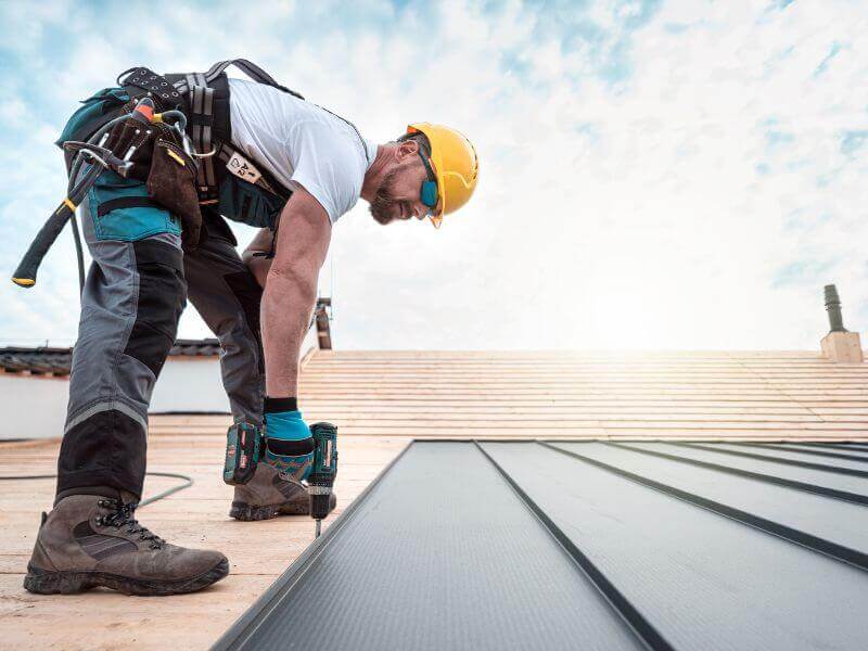 man using drill while installing standing seam panels