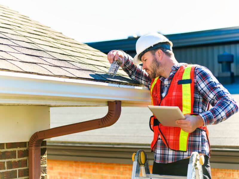 roofer checking shingles for roofing job requirements