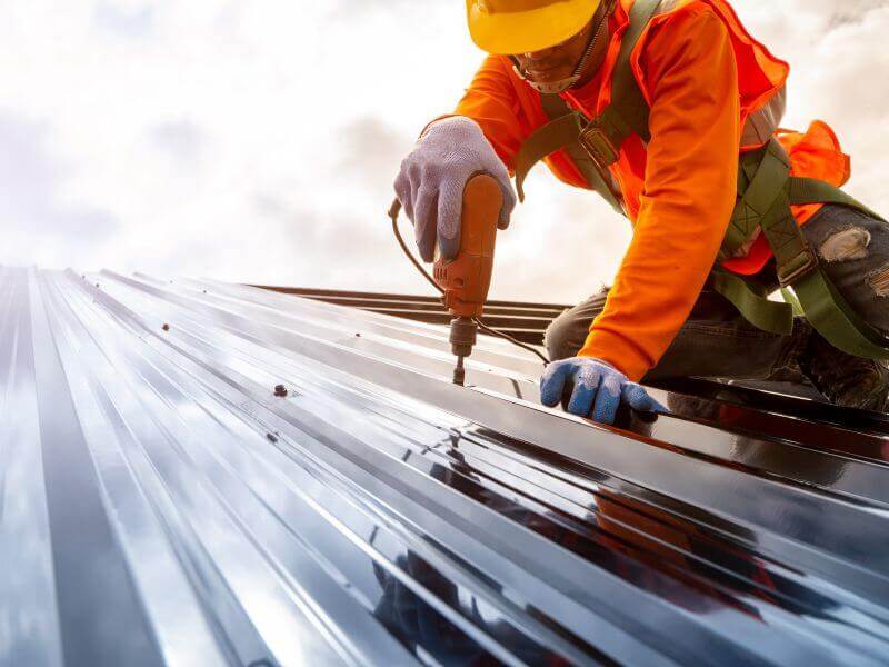 worker drilling metal roof meets roofing job requirements