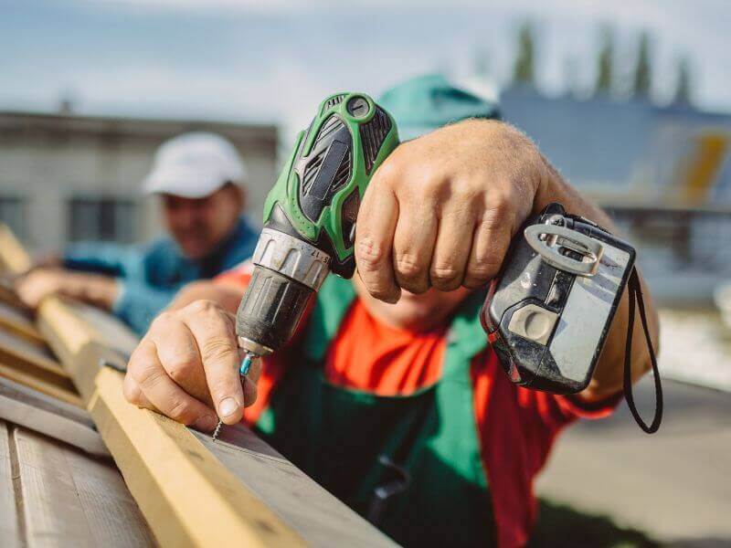 close-up of hands drilling into wood during roof work