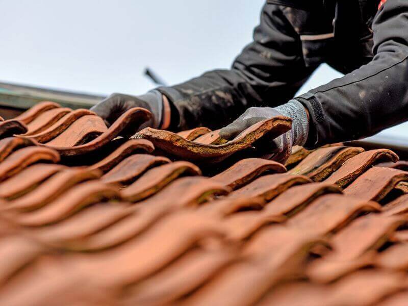 hands adjusting tiles in line with roofing standards